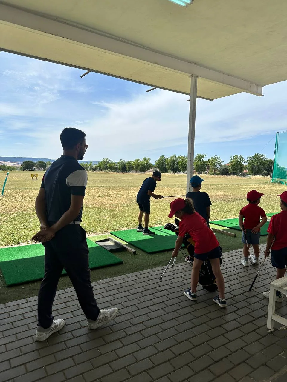 Monitor con jóvenes jugadores en el driving range